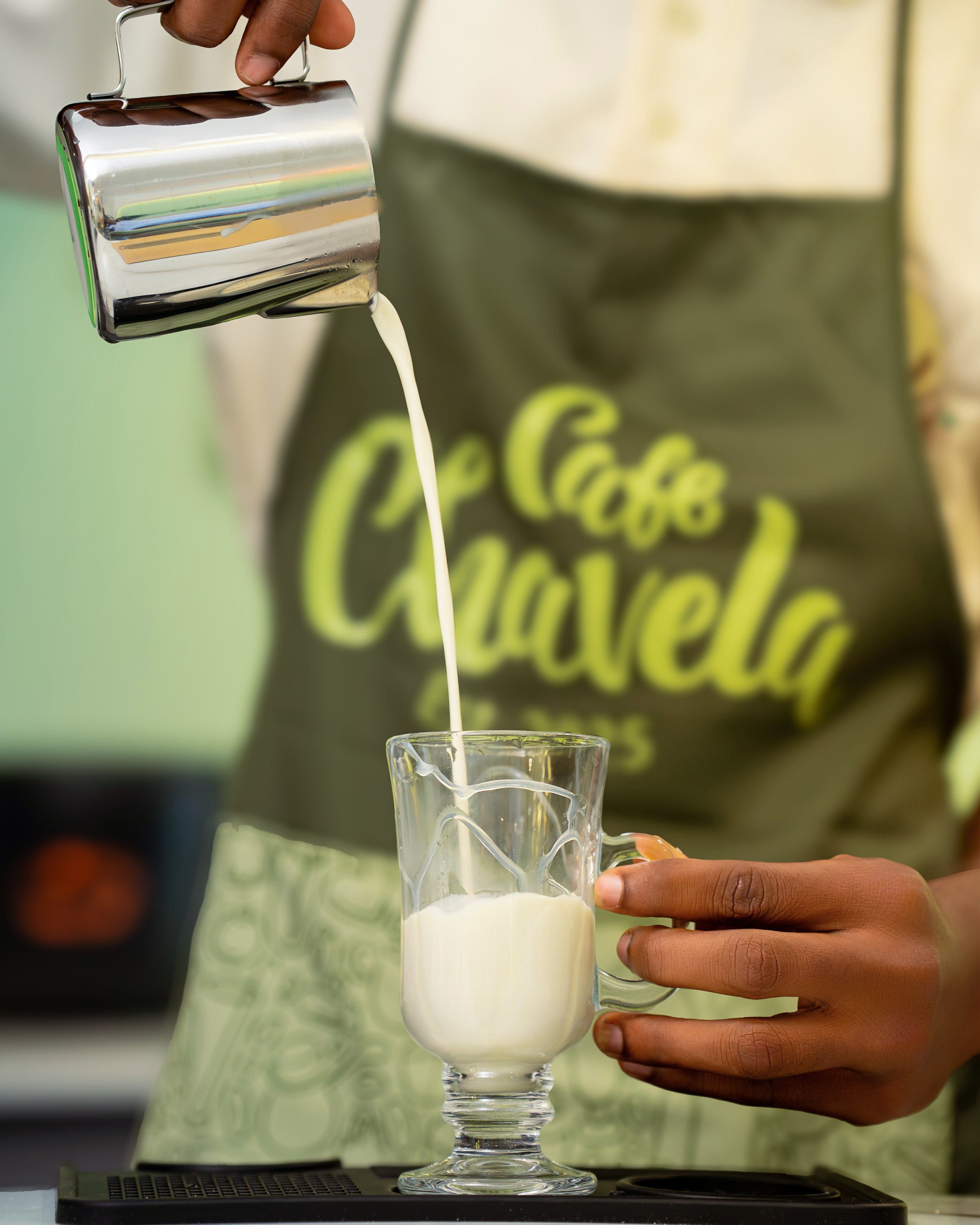 Barista pouring steamed milk into a glass